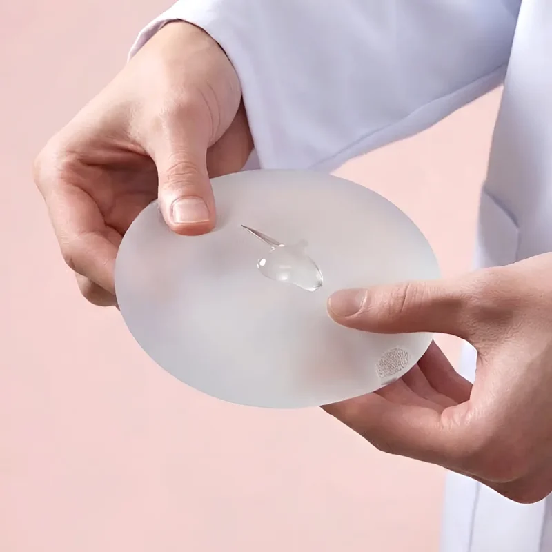 Surgeon holding a breast implant during a PIP implant exchange consultation